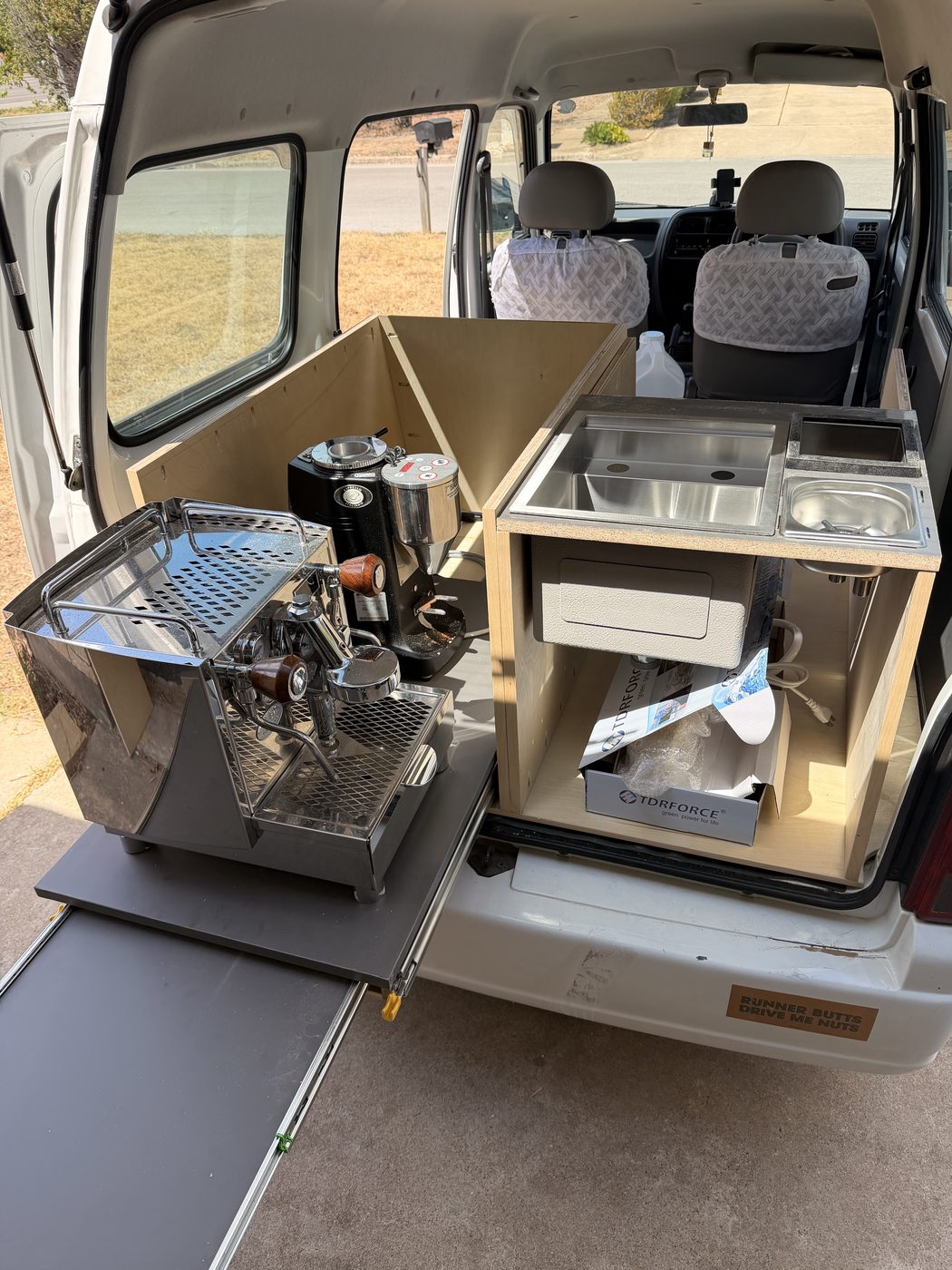The hatch bar in the shop: a slide-out machine and a plywood sink.