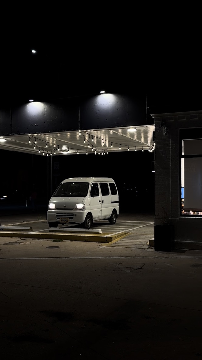 Steve, a white 1999 Suzuki Every, parked at night under string lights.